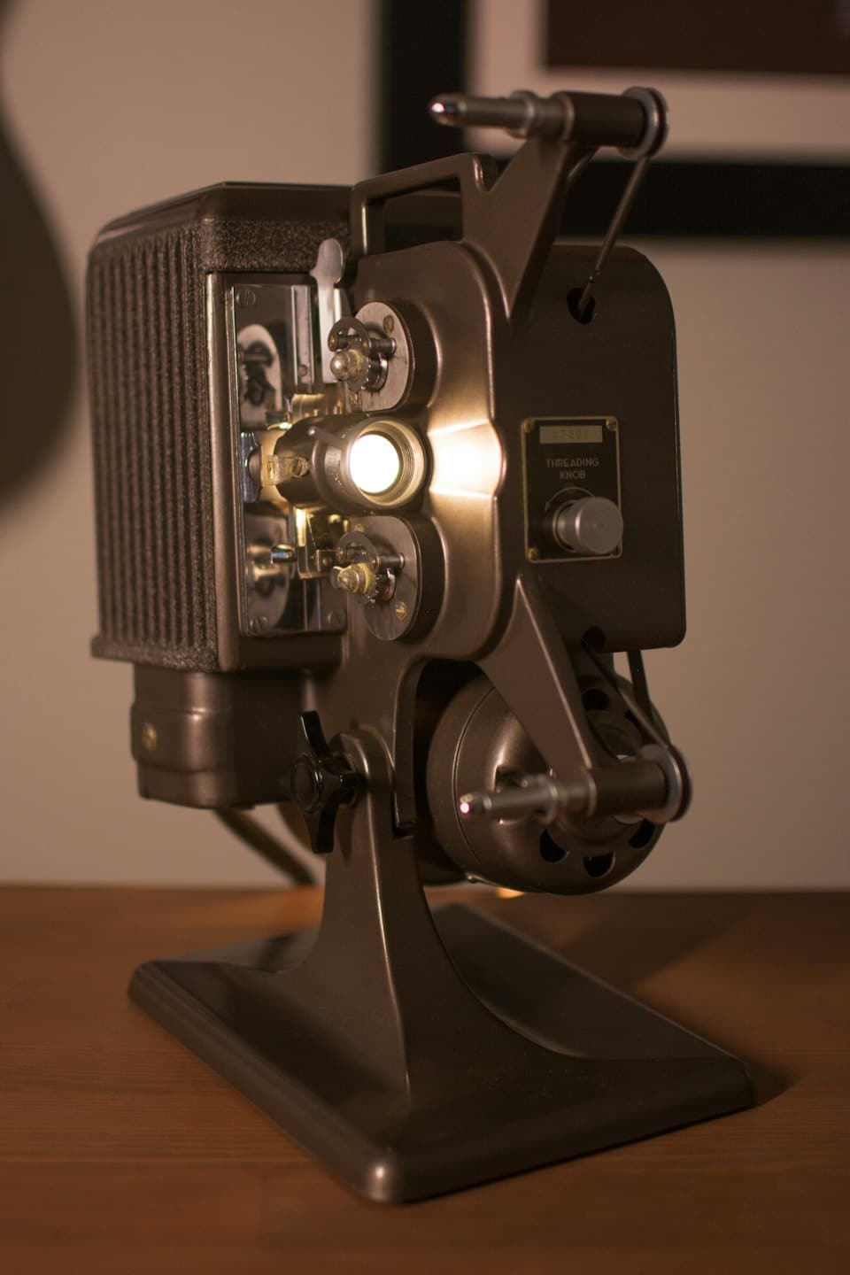 Vecchia pellicola cinematografica con luce che esce dall'obiettivo su un tavolo di legno.