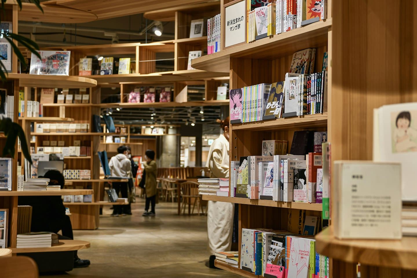 Persone che sfogliano libri in una moderna libreria con interni in legno.