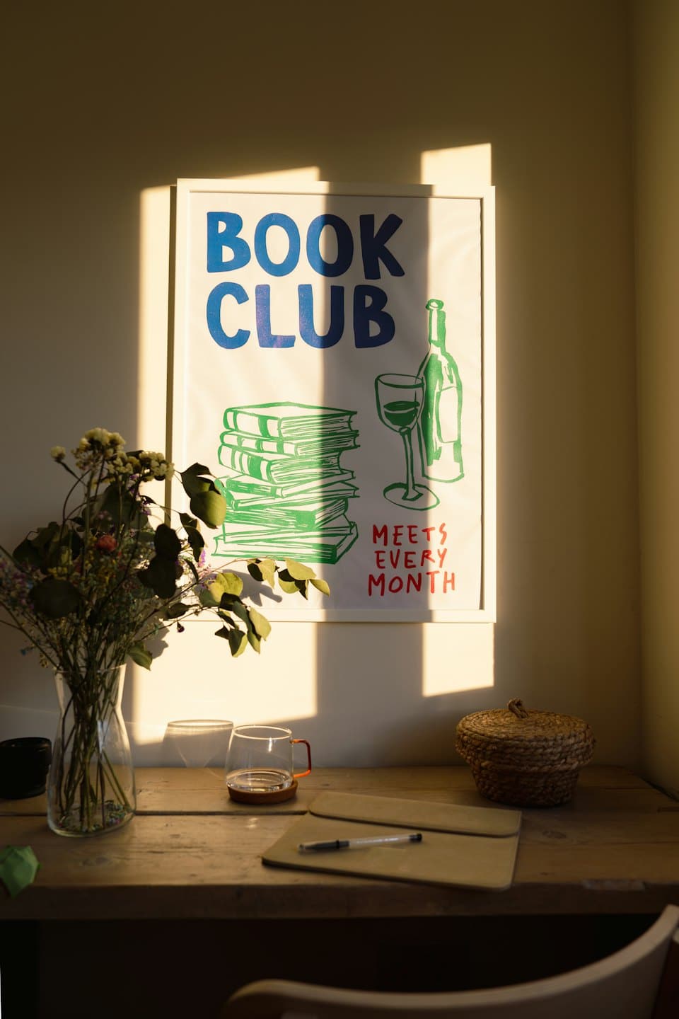 Scrivania con poster di un club del libro e composizione floreale.