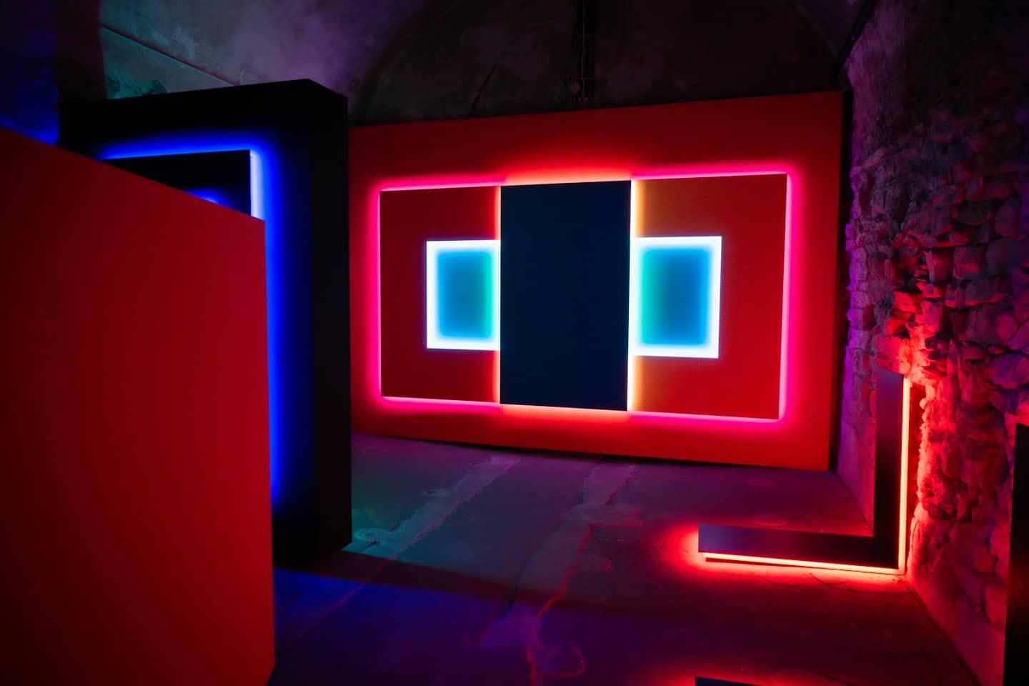 Installazione artistica astratta con forme geometriche luminose e luci al neon.