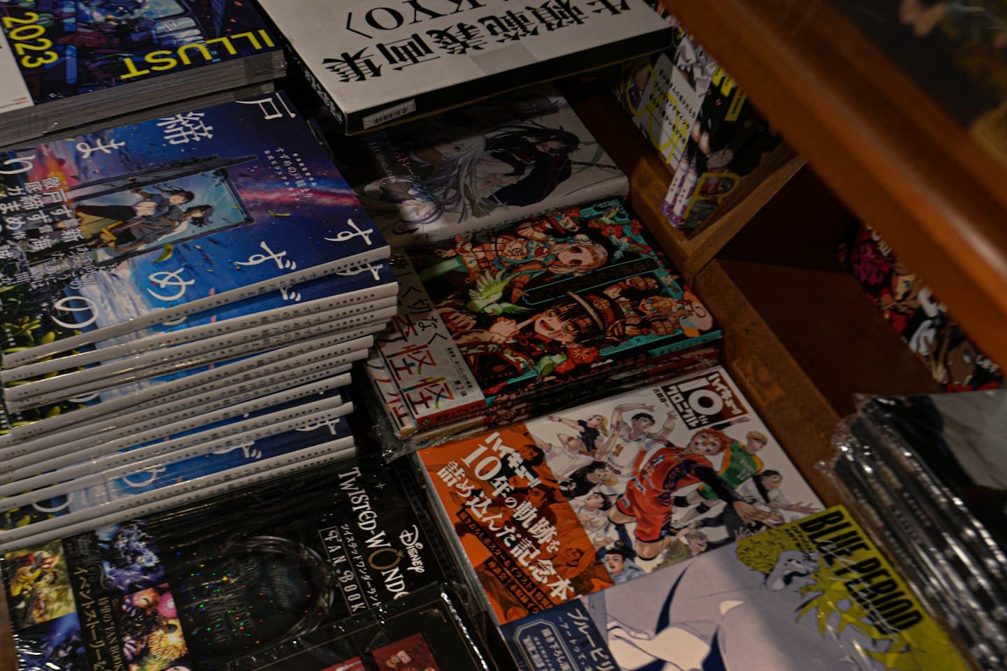 Libri manga e d'arte giapponesi su scaffali di legno scuro in una libreria.