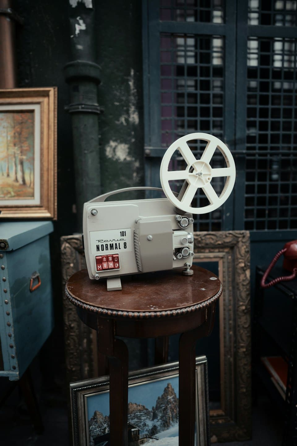Proiettore cinematografico vintage appoggiato su un tavolo rotondo di legno.
