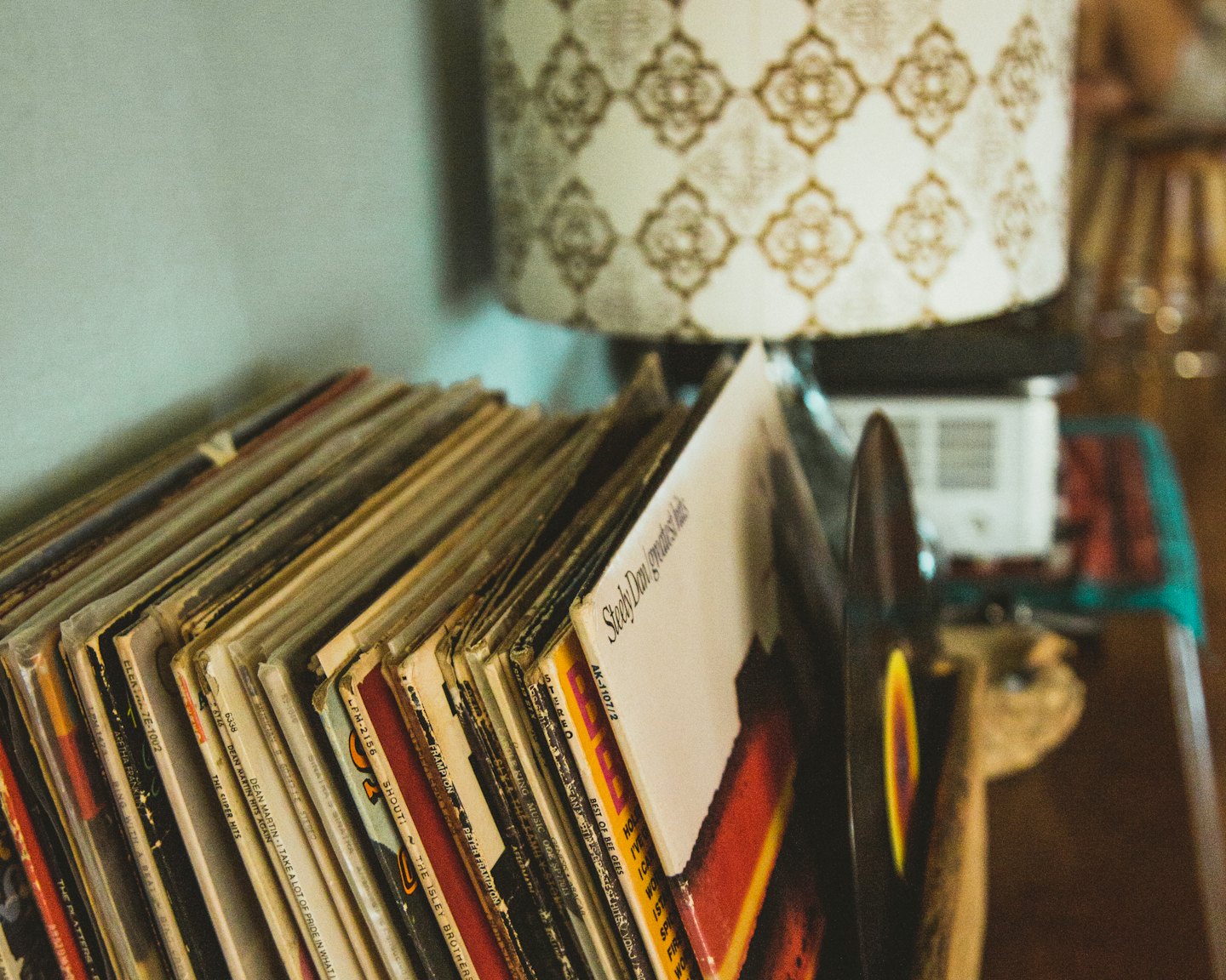 Pila di dischi in vinile vintage al chiuso accanto a una lampada.